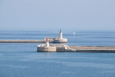 Lighthouse by sea against sky