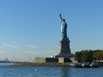 Statue of liberty by hudson river against blue sky