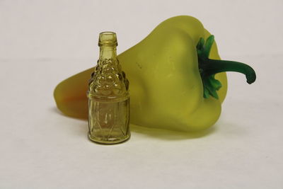 Close-up of green bottle on table against white background