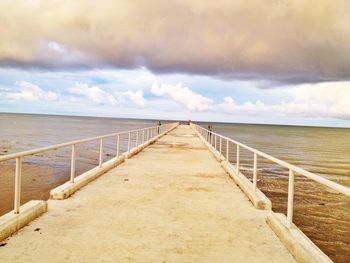 Pier on sea against cloudy sky