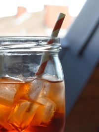 Close-up of cocktail with ice cubes and straw in mason jar