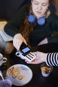 Young woman paying with phone in cafe