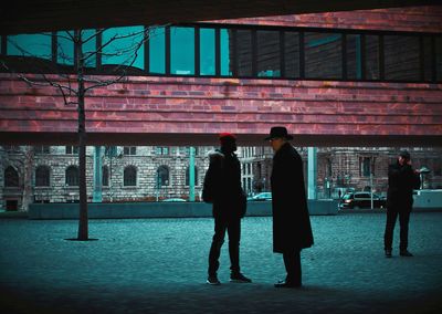 Rear view of people walking on sidewalk in city