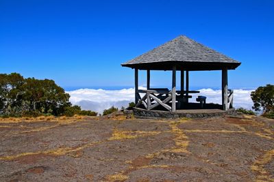 Gazebo on landscape against blue sky