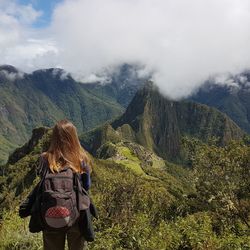 Rear view of female hiker standing against mountains