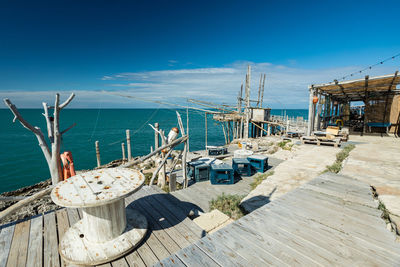 Sailboats moored on pier by sea against blue sky