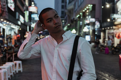 Portrait of young man standing on street in city at night