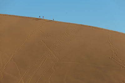 Scenic view of sandy desert against clear blue sky