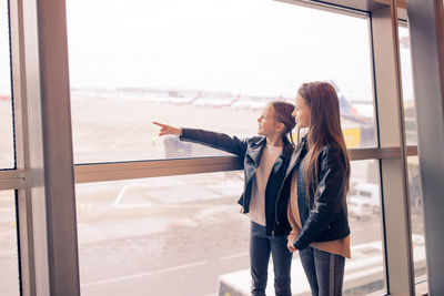 Sisters looking through window