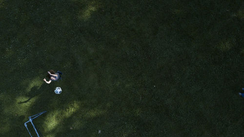 High angle view of girl playing with ball while standing on grassy field at park