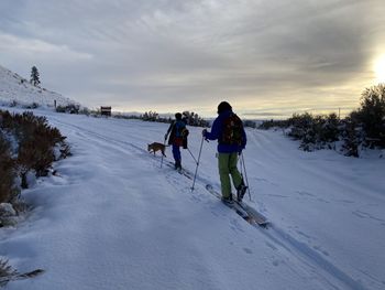 Rear view of people on snow field against sky