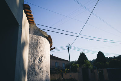 Low angle view of electricity pylon against blue sky