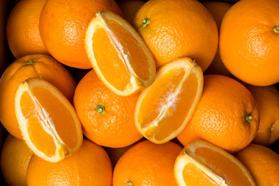 A top down view of a case of fresh navel oranges with an orange cut into quarters on top.