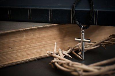 A cross with holy bible with a thorn crown over the dark background. 