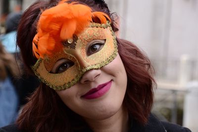 Portrait of woman wearing orange masquerade mask