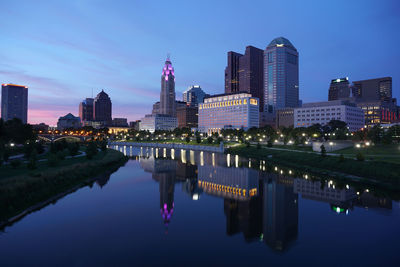 Reflection of illuminated buildings in city at dusk