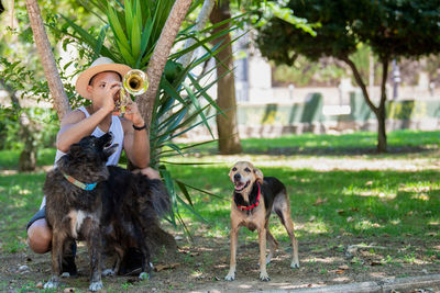 Man playing trumpet with dog at park