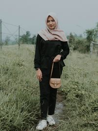 Portrait of young woman standing on field