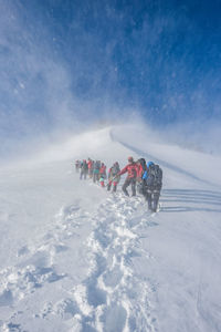 Low angle view of people hiking on snowcapped mountain