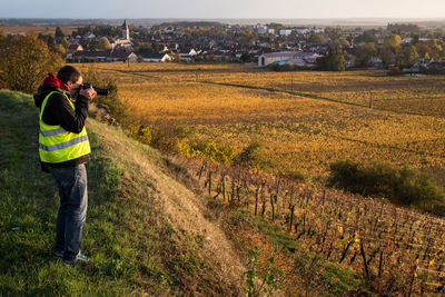 Side view of man photographing while standing on field