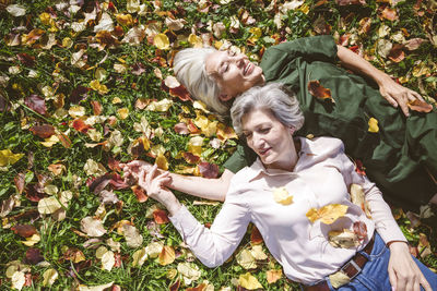 Happy women smiling while lying on grass at public park