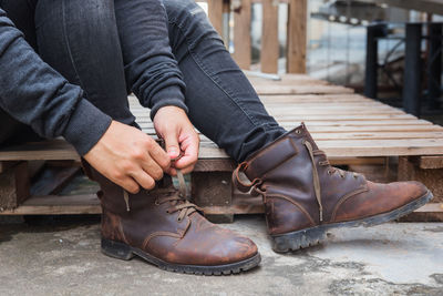 Low section of man tying shoelace while sitting on palette