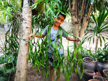 Portrait of smiling young woman standing by plants
