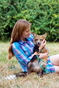 Woman holding fox on grass