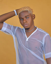 Portrait of young man standing against yellow background