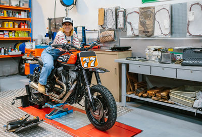 Mechanic woman leaning over motorcycle on factory