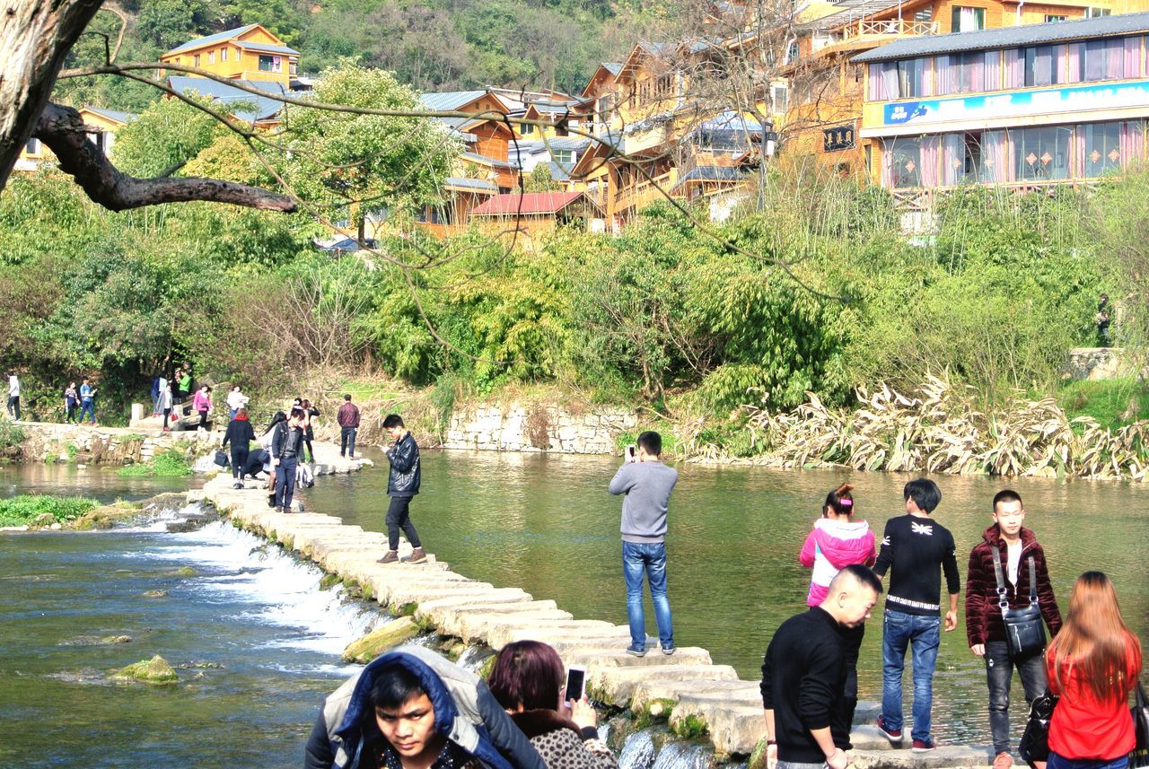 lifestyles, large group of people, leisure activity, men, building exterior, architecture, person, built structure, tree, water, high angle view, togetherness, mixed age range, tourist, grass, enjoyment, day, vacations, casual clothing