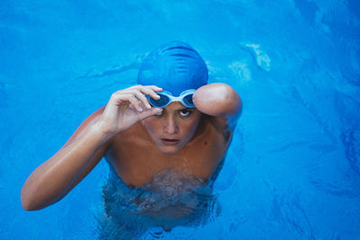 Portrait of young paralympic swimmer putting on swimmming goggles