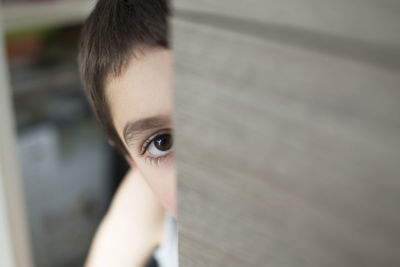 Boy looking away while peeking by door