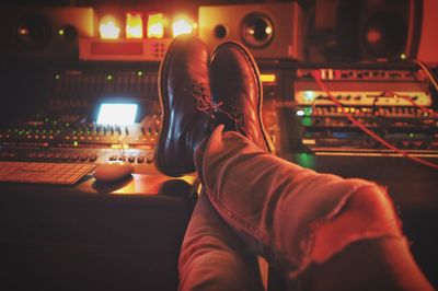 Low section of man with crossed legs on sound mixer at studio