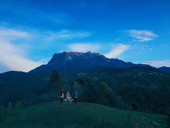 People on mountain against blue sky