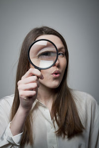 Portrait of young woman holding eyeglasses against white background