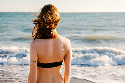 Rear view of woman at beach against sky