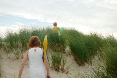 Rear view of girl walking standing on sand at beach