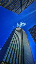 Low angle view of skyscraper against blue sky