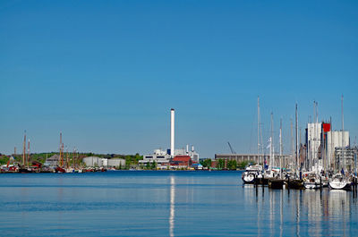 Sailboats in harbor against clear blue sky