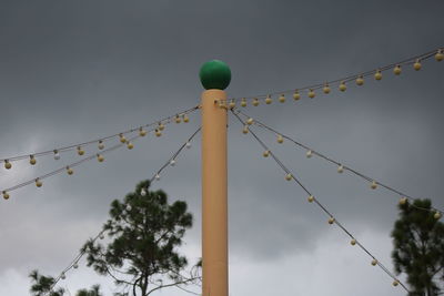 Low angle view of illuminated lighting equipment on pole against sky