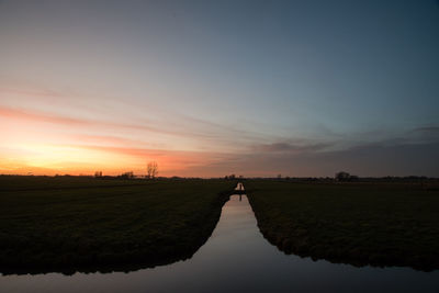 Scenic view of agricultural field against sky during sunset