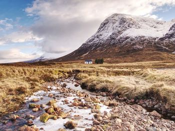 River at base of snowy mountains in scottish highlands near glencoe in winter. cold winter morning