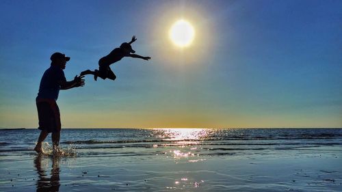 Silhouette of father and son playing on beach