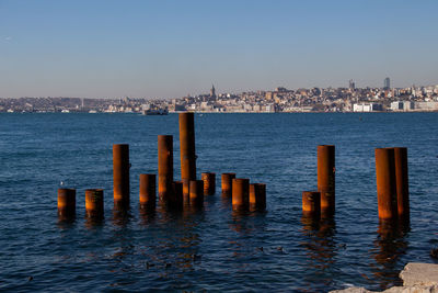 Sea and buildings in city against clear sky