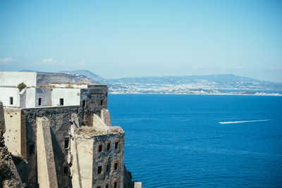 Old building by sea against sky