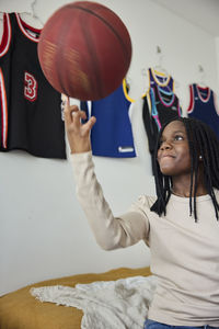 Smiling girl in bedroom balancing basketball