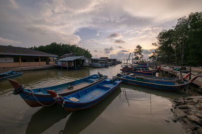 Boats moored in water at sunset