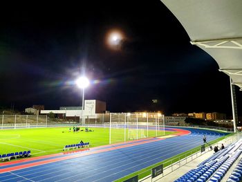 Group of people relaxing on field against sky at night