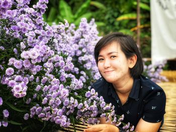 Portrait of smiling woman against purple flowering plants
